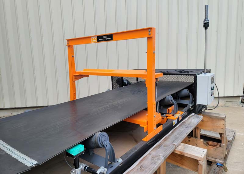 Eriez 1230 metal detector on trough belt conveyor. Orange metal detector with control and reject beacon.